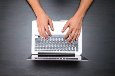 Bir adam vintage ahşap masa üzerinde bir dizüstü bilgisayar kullanarak çalışıyor. Tipik bir klavye üzerinde eller. Üstten görünüm, iş Ofis İşyeri