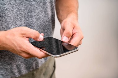 Metniniz için boş kopya alanı ekranlı akıllı cep telefonu tutan adamın elleri görüntüsünü kapatın. Üniversitesi'nde derslere sonra kafede otururken cep telefonunda bir mesaj yazarak öğrenci