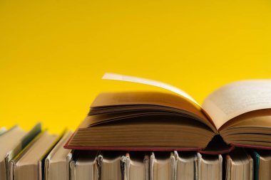 Sarı arka planlı, ahşap masa ciltli kitap açık kitap. Eğitim ve arka plan öğrenme. Okul için okuyor. Metin için yer kopyalayın