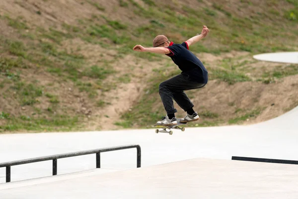 Young skateboard athlete doing a jump in a concrete skatepark. Extreme sport recreation activity for youth. Man doing a stunt on a skateboard. Urban sport, staying out of trouble