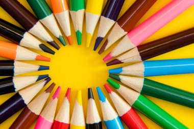 Bir sürü daire, sarmal sarı arka plan üzerinde renkli kalemler. Okul malzemeleri, yaratıcılık kavramı