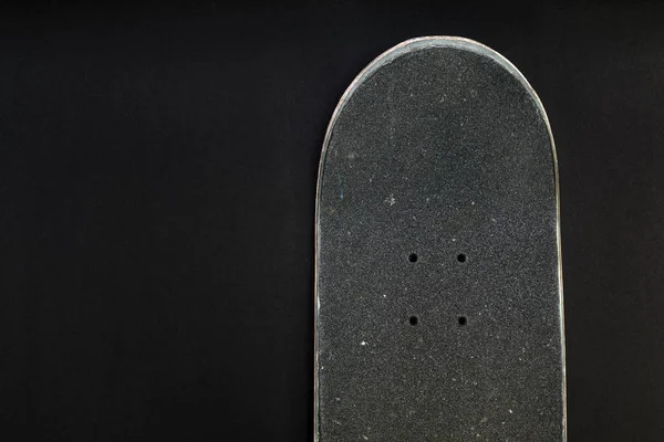 Front top of a skateboard deck with grip tape and bolt holes on black background