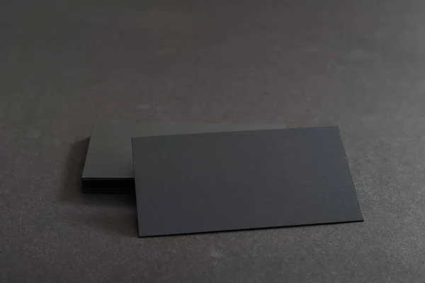 Photo of black blank business cards on a black background. Template for ID. Top view