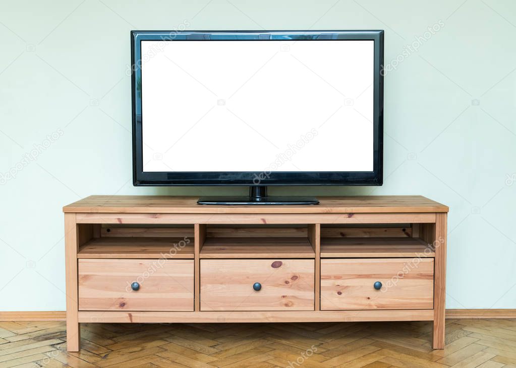 Flat LCD television on brown wooden cabinet in the living room with a white screen for copy text 