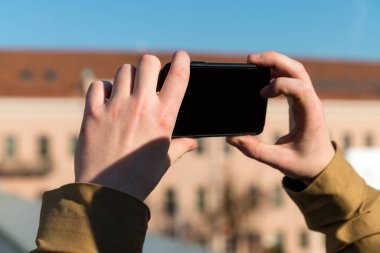 Genç adam bir telefon ve çekici fotoğraf bir akıllı telefon ile açık havada tutuyor