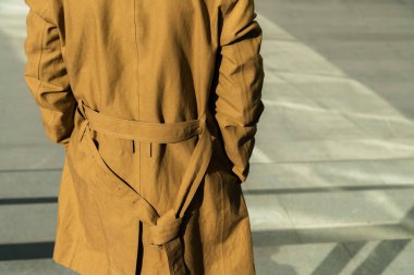 Ayakta açık ve giyen şık kahverengi ceket gri beton geçmişi olan genç adam