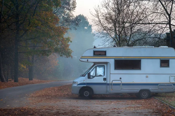 Old camper van parked in next to the road on foggy and cold autumn morning