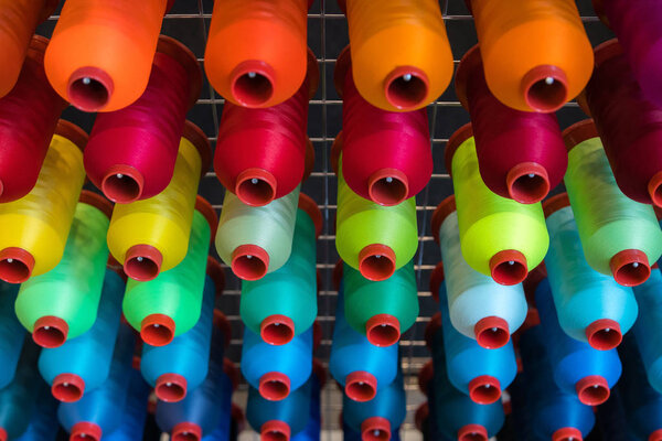 Colorful embroidery thread spool using in garment industry, row of multicolored yarn rolls, sewing material selling in the market