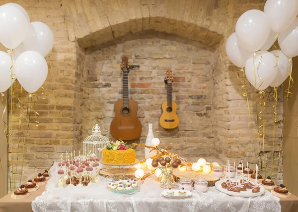 Birthday room with balloons, guitars and sweets on the table, cake, candies. Cozy atmosphere