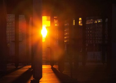 Warm red sun shines through concrete poles. Evening sunset in construction site in Spain