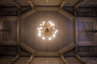 Looking up at old church ceiling. Chandelier light and classic indoor decorations