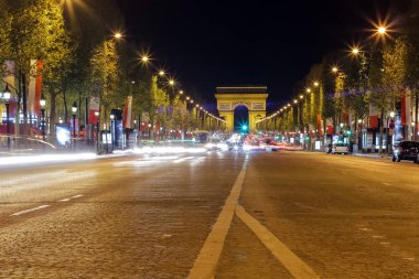 Arc de triomphe in Paris, France during rush hour at night. Traffic lights, tourist attraction 