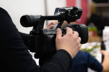 Covering an event with a video camera. Videographer films with video camera. Camera operator working indoors