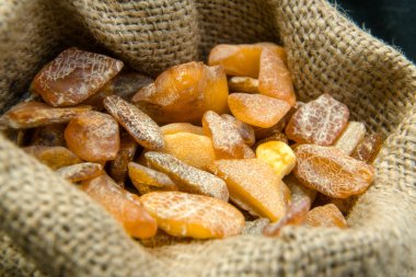 Baltık Denizi keten çantasından bir kehribar taş yakın çekim. Reklam ve afiş için çok renkli arka plan. Arka plan olarak Vintage fosilleşmiş reçine. Kırmızı amber yakın. Taş kapanımlar ile