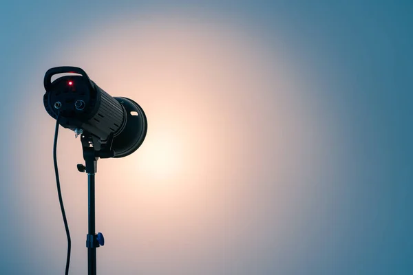 Studio light on the stand. Spotlight on white wall background. Copy space for text