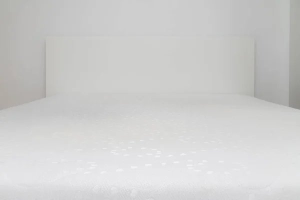 Close up of memory foam mattress on the bed frame at sleeping room. Comfort, choosing mattress