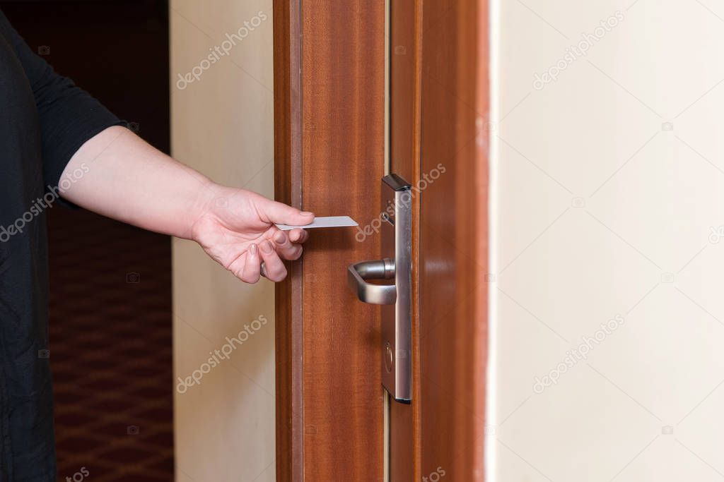 Female hand putting key card switch in to open hotel room door. Holding magnetic card for door access control scanning key card to lock and unlock door