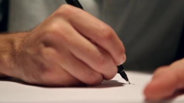 Adam çizim veya beyaz kağıda yazılı. Bir gömlek giymiş ve masanın arkasında kağıt üzerinde yazılı iş makro çekim