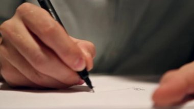 Adam çizim veya beyaz kağıda yazılı. Bir gömlek giymiş ve masanın arkasında kağıt üzerinde yazılı iş makro çekim