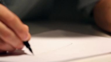 Adam çizim veya beyaz kağıda yazılı. Bir gömlek giymiş ve masanın arkasında kağıt üzerinde yazılı iş makro çekim