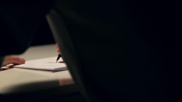 L'homme dessine ou écrit sur une feuille blanche de papier. Macro shot d'affaires portant une chemise et écrivant sur du papier derrière le bureau 