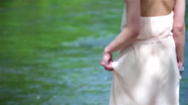美しいブロンドの女の子はドレスと花の花輪を身に着けている川に向かって歩いて頭の上 ブライダル 結婚式の日 — ストック動画