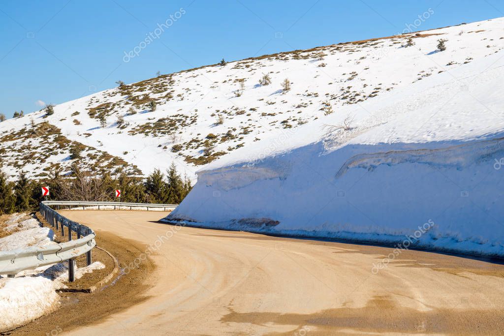 Car driving on narrow road in Beklemeto pass, Balkan mountains, Bulgaria. Melting snow in spring time, dangerous driving condition