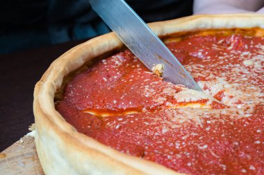 Chicago pizza üst görünümü. Kadın elleri domates sosu ve sığır eti ile Chicago tarzı derin çanak İtalyan peynir pizza kesme içinde karşılamak