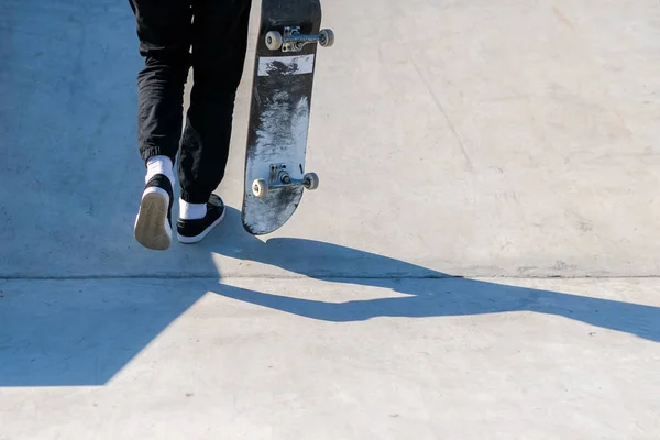 Joven atleta de skate subiendo por la rampa mientras sostiene un monopatín. Practica freestyle, actividad deportiva urbana extrema para jóvenes, manteniéndote alejado de los problemas — Foto de Stock