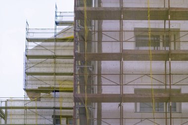 Bina cephe yenileme, eski ev yeniden yapılanma, onarım. Sarı şeffaf kumaşla kaplı binanın cephesi önünde iskele