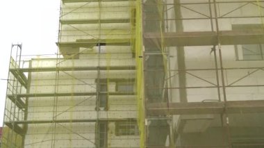 Bina cephe yenileme, eski ev yeniden yapılanma, onarım. Sarı şeffaf kumaşla kaplı binanın cephesi önünde iskele