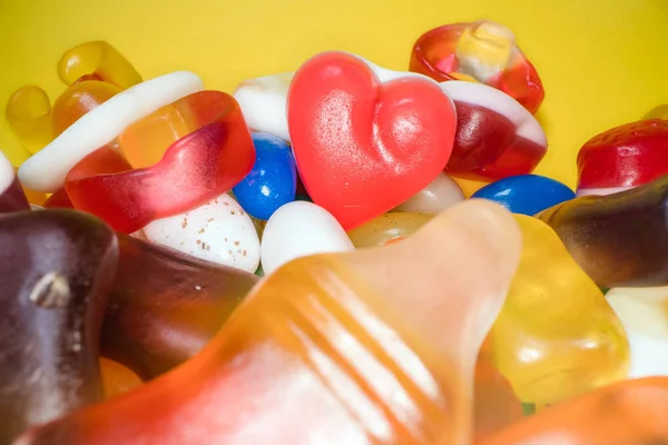 Mucchio di deliziose caramelle colorate da masticare sfondo. Dolci colorati su sfondo giallo — Foto Stock