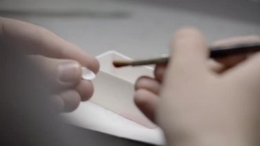 Takma dişler üzerinde çalışan diş teknisyeni ellerinin yakın çekimi. Profesyonel diş laboratuarında bir fırça ile diş ve fırça tutar