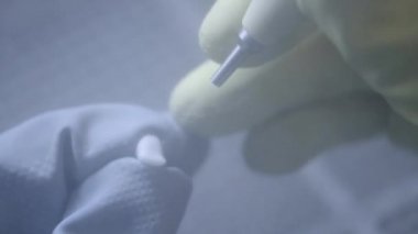 Diş laboratuarında kum blaster kullanarak yapay seramik dişleri parlatma diş teknisyeni. Profesyonel elinde sahte dişler tutarak ve kum blaster ile parlatma sırasında eldiven giyiyor