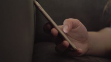 Elinde akıllı telefon tutarken bir kanepede genç kız. Genç kız üzerinde kaydırma 