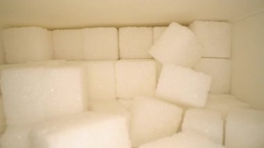 Tahta masa üzerinde karton kutuiçine sonraki şeker küpleri ile kayma Makro dolly vurdu. Sağlıksız gıda tatlandırıcı, tatlı kristal küpler