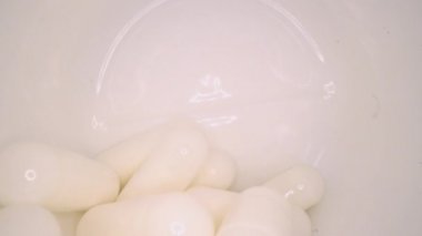 Beyaz haplar veya kapsüller ahşap masa arka plan üzerinde şişe yanında. İlaç reçetesi, tedavi ilaçları. İlaç tedavisi, sağlık için konteynerde tedavi. Ağrı kesiciler, baş ağrısı, depresyon