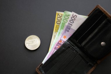 Siyah arka plan üzerinde bir cüzdan dışarı yapışmasını Euro banknotlar yanında Dash sikke. Dijital para birimi, blok zinciri piyasası. Kripto sikke yanında Euro faturaları