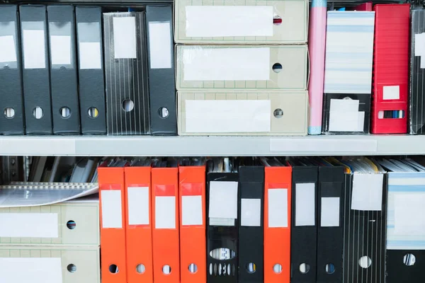 Colourful blank blind folders with files in the shelf. Archival, stacks of documents at the office or library. Physical document storage units