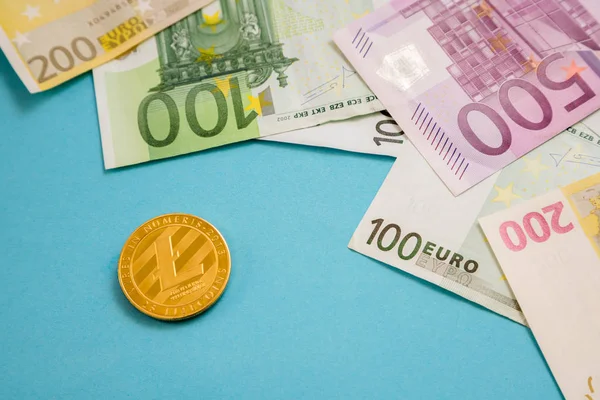 Litecoin coin next to Euro bank notes on blue background. Digital currency, block chain market. Euro bills next to crypto coin — Stock Photo, Image