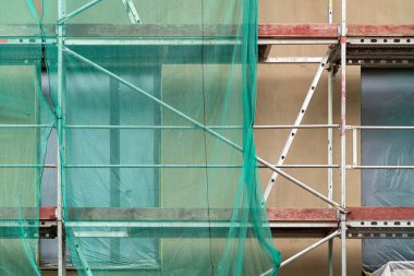 Bina cephe yenileme, eski ev yeniden yapılanma, onarım. Sarı şeffaf kumaşla kaplı binanın cephesi önünde iskele