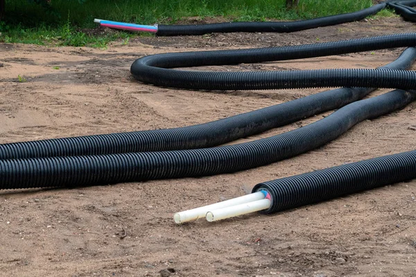 Schwarze PVC-Elektrorohre mit Drähten am Boden. Baustelle, Stromleitung mit Kabeln — Stockfoto