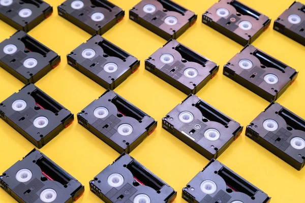 Cintas de cassette mini DV vintage utilizadas para filmar en un día. Patrón hecho de cintas de vídeo de plástico sobre fondo amarillo —  Fotos de Stock