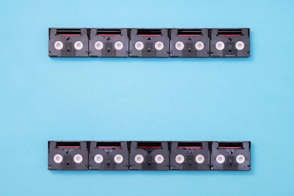 Analog film screen concept made of vintage mini DV cassette tapes used for filming back in a day. Pattern made of plastic video tapes on blue background