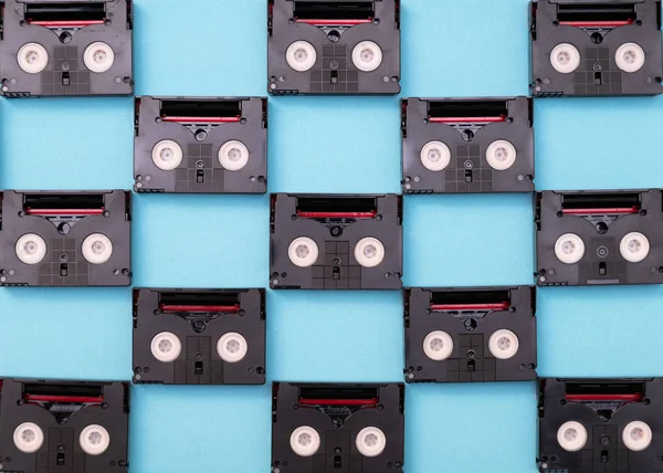 Cintas de cassette mini DV vintage utilizadas para filmar en un día. Patrón hecho de cintas de vídeo de plástico sobre fondo azul —  Fotos de Stock