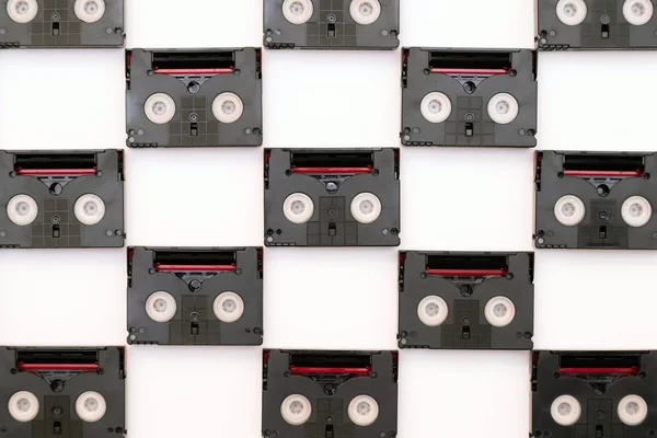 Vintage mini DV cassette tapes used for filming back in a day. Pattern made of plastic video tapes on white background
