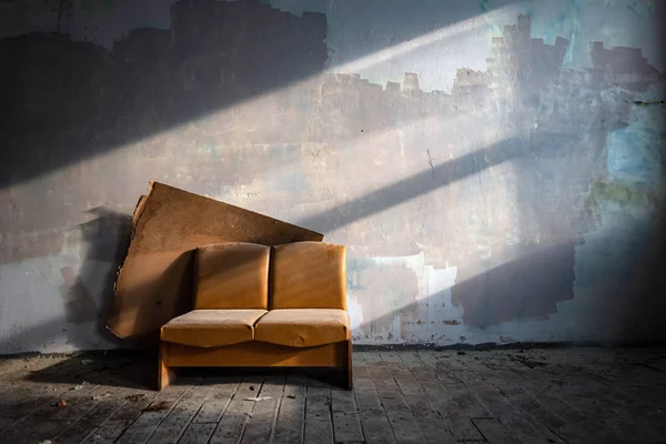 Terk edilmiş fabrika binasının yanındaki eski deri kanepe güneşle aydınlatılmış. Perili evde taşralı mobilyalar — Stok fotoğraf