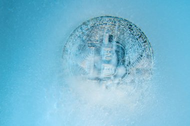 Silver Bitcoin, bit coin online digital currency frozen in the blue ice. Concept of block chain, crypto market crash. Frozen crypto money, depreciation clipart