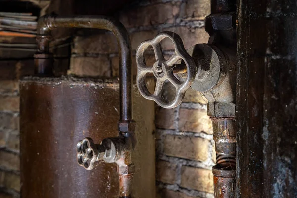 Rusty boiler room pipes. Old metal boiler generating heating and delivering it to home through pipeline. Hot water or gas is being delivered with this system