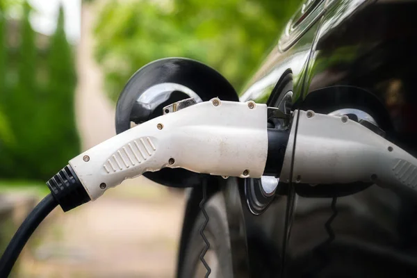 Βύσμα φορτιστή σε ηλεκτρικό αυτοκίνητο σε πράσινο περιβάλλον φόντο. Νέο ενεργειακό όχημα, το NEV φορτώνεται με ηλεκτρική ενέργεια. Οικολογία, σύγχρονα αυτοκίνητα — Φωτογραφία Αρχείου